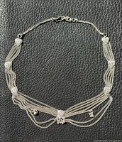 Full view of silver-tone multi-strand heart necklace on dark background