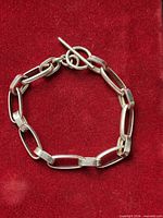 Full view of sterling rectangular link bracelet on red background
