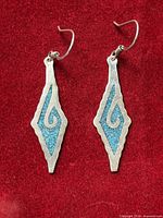 Front view of both sterling silver earrings on red background