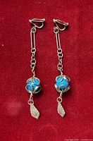 Full view of both sterling silver clip-on earrings on red background