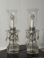 Both crystal hurricane lamps unlit on table