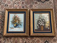 Both framed floral oil paintings side by side