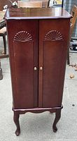 Front view showing carved doors and Queen Anne legs