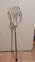 Full view of Under Armour lacrosse stick leaning against wall