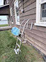 Full ladder leaned against building showing three steps and curved handrails