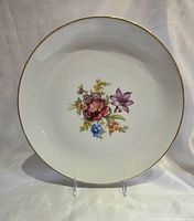 Front of white porcelain plate with floral design and gold rim