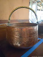 Front view of copper pot showing engraving and brass handle