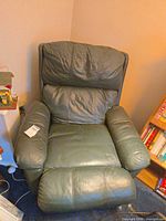Front view of dark green leather recliner showing overall form and wear