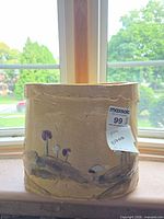 Front view of beige ceramic planter showing painted landscape motif and overall shape
