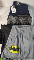Stack showing Batman shorts, black garment, grey heather shorts, navy Russell shorts