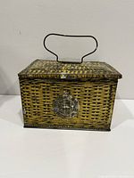 Front view showing overall form, basket-weave lithography, wire handle, starburst seal