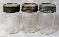 Front view of three Crown mason jars showing embossed design and lids