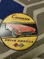 Front view of round tin Corvette sign showing full graphic and wear
