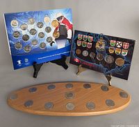 Two illustrated cardboard coin boards on easels, left with 17 Olympic quarters, right with 13 Confederation quarters.