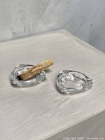 Both clear glass ashtrays on surface, one holding a smoldered wood stick