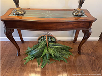 Front view of wooden console table with glass inset top and carved legs