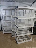 Two of the three white plastic shelving units assembled in garage