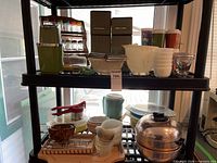 Overall lot on shelving showing canisters, spice rack, tumblers, bowls, bakeware and tools