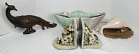 Group view: metal peacock, pottery bowl, floral bookends, shell decor