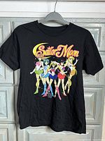 Front view of black Sailor Moon graphic T-shirt on hanger