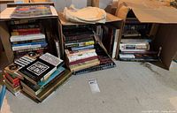 Three groups of books in boxes and tote bag visible