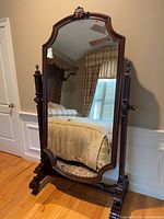 Full view of cheval mirror showing carved mahogany frame and mirror glass