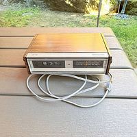 Front view showing flip clock display, radio dial, and AC cord