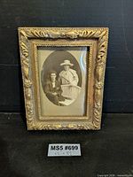 Front view of ornate gold gilded frame with sepia photograph
