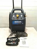 Front view of Mastercraft air compressor with hose, accessories, manual