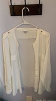 Front view of white Calvin Klein blouse on hanger