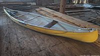 Full view of yellow aluminum Cadorette canoe resting on wooden floor