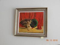 Framed signed oil painting depicting a nude female figure with a large fan and red fabric backdrop. The painting is signed 'Daniken' and dated 1950 in the lower right corner, displayed hanging on a wall.