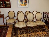 Seven oval back chairs arranged in two rows, showing wooden frames and patterned upholstered seats and backs.