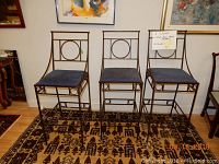 Photo of three custom made hand welded metal bar stools, each with a blue cushioned seat and geometric metal backrest design.