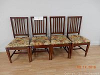 Photo of 4 wooden dining chairs with floral patterned seat cushions.