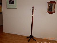 Full view of the antique wooden coat rack showing its height and base design.