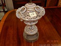 Top angle photo of antique Asian motif table lamp showing decorative bird figures and floral cutout patterns on a beige ceramic body.