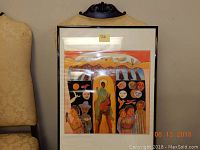 Framed print by Betty Laduke from 1978 with bright orange, red, black, and yellow tones showing stylized human faces and figures.