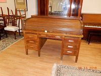 Front view of the oak roll top desk showing six drawers and roll top closed.
