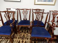 Five wooden dining chairs with blue upholstered seats arranged on a patterned carpet. Two armchairs, one with broken armrest visible on left side.
