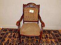 Full view of the wooden armchair showing the upholstery and armrests.