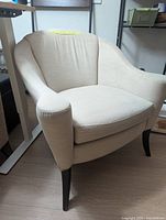 Front three-quarter view of off-white armchair showing upholstery and legs