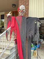 Full view of hanging clown prop on stair railing showing overall size and colors