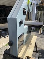 Side view of Delta band saw on stand showing model plate and housing