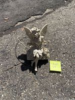 Full view of fairy statue on pavement with swing ropes