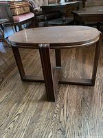 Side view of dark walnut oval wooden accent table on hardwood floor