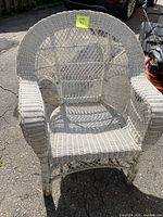Front view of white wicker/rattan armchair showing arched back and rolled arms