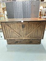 Closed cabinet bed front view showing rustic barn-door panels and drawer