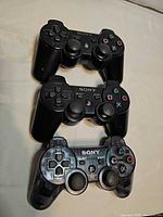 Front view of three Sony DualShock 3 controllers stacked