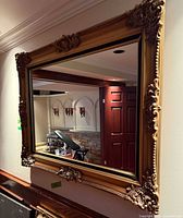 Full view of rectangular gilt mirror mounted on wall